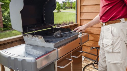 A man is cleaning grill grates with a wire brush